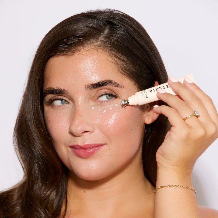 Woman applying eye serum to her face with a silver applicator.