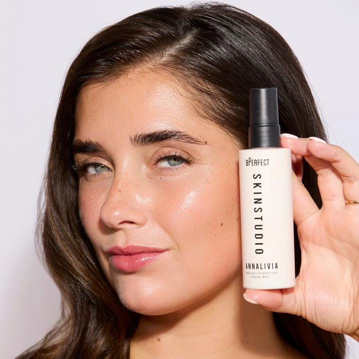 Person holding a Skin Studio product near their face against a plain background