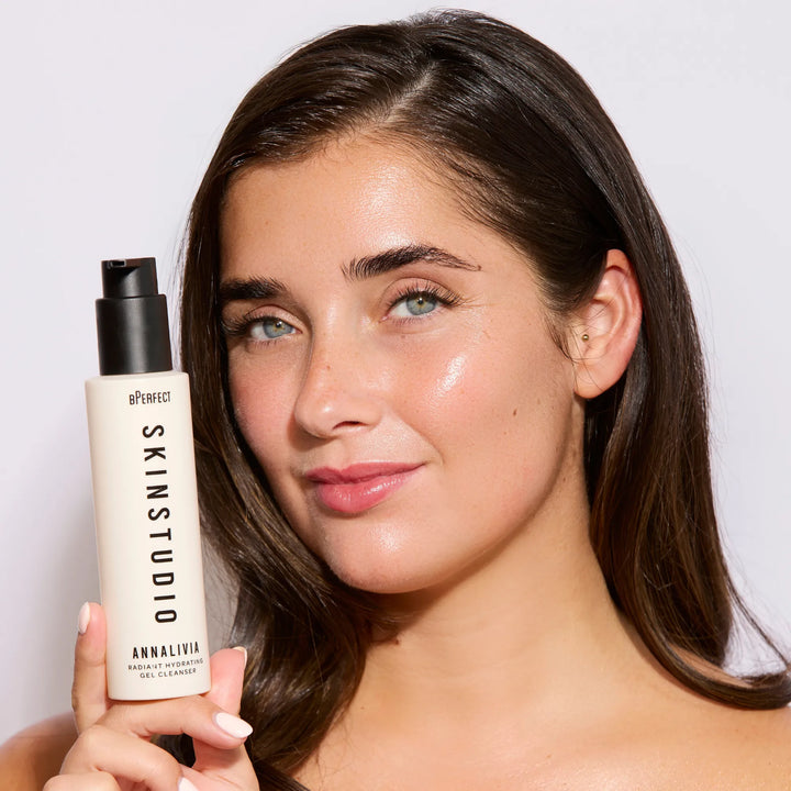 Woman holding a Skin Studio skincare product against a plain background