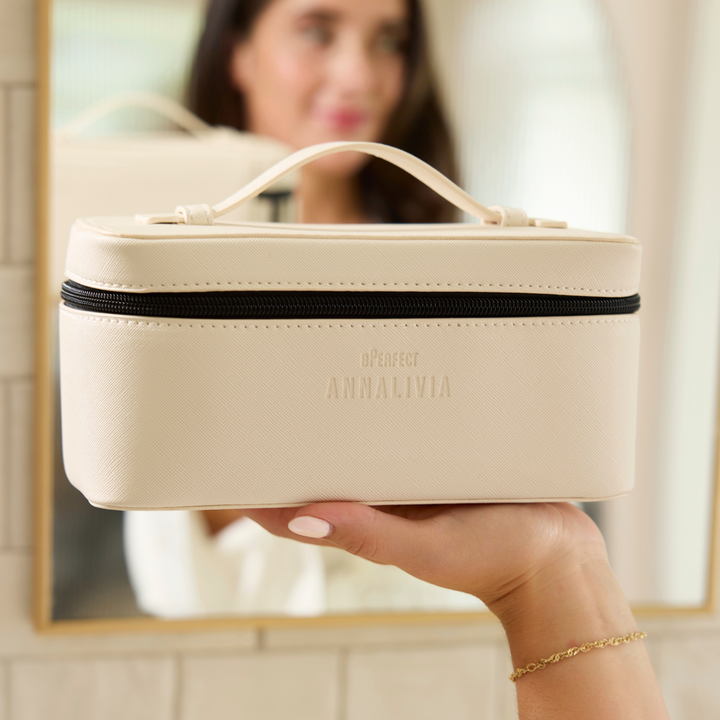 Beige travel case held by a hand with a blurred background