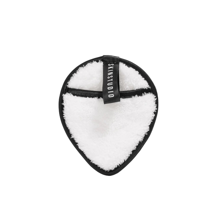 Tear-shaped white cleaning pad with black border and 'SKINSTUDIO' branding on a white background
