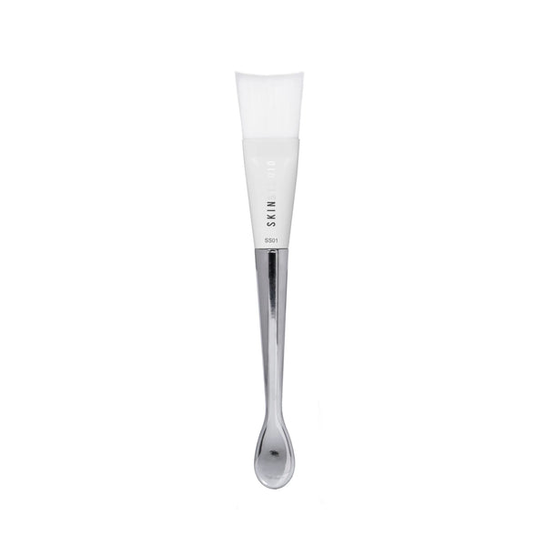 Skincare brush with silver applicator and a white brush on a white background