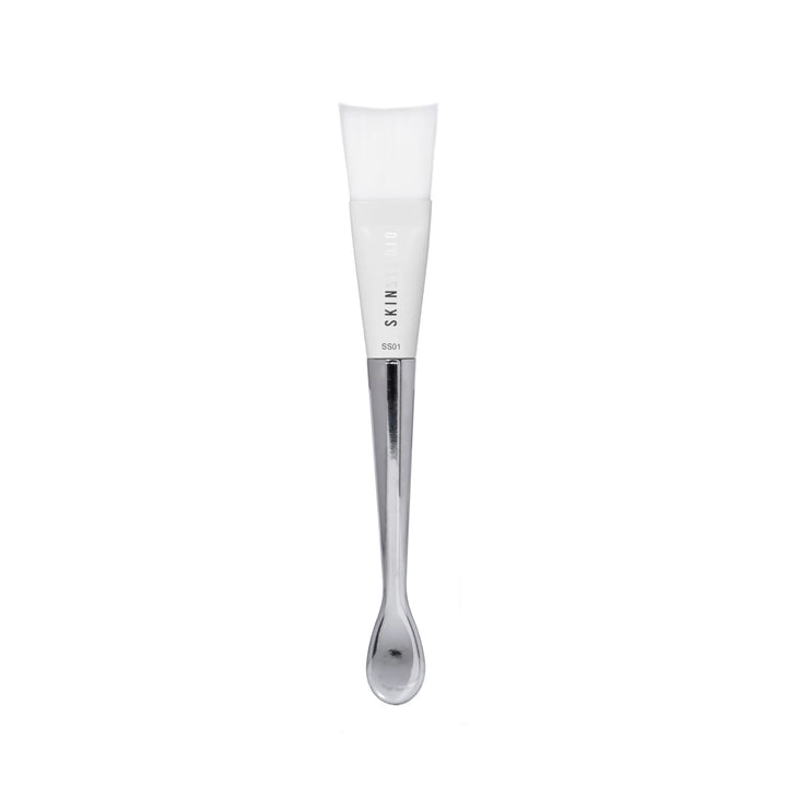 Skincare brush with silver applicator and a white brush on a white background