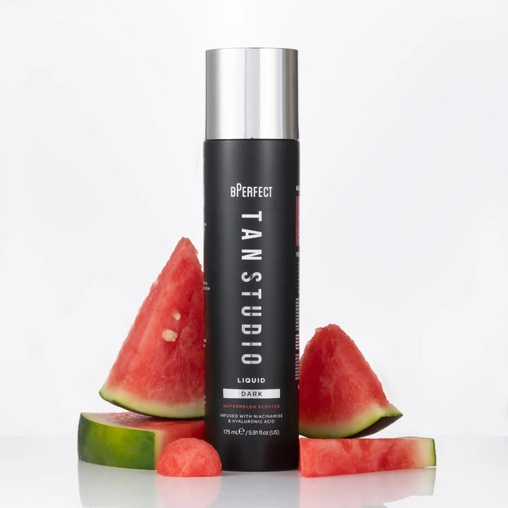 BPerfect Tan Studio Liquid tan in a black bottle with silver cap and watermelon on a white background