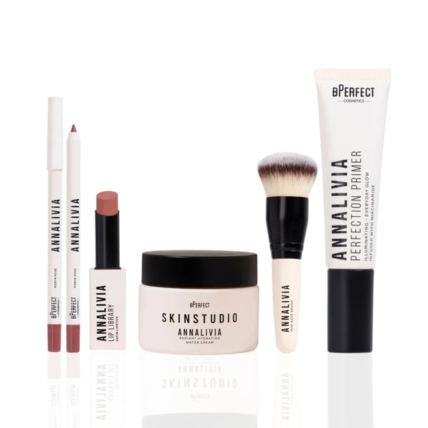 Collection of cosmetic products including a jar, a tube, lip products, and a brush on a white background